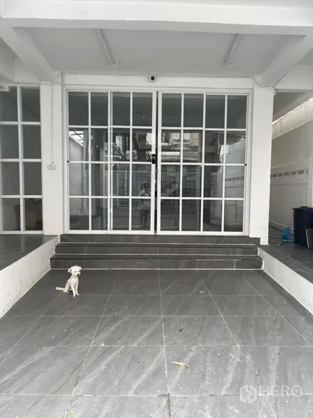 Townhouse for sale in Din Daeng, Bangkok - Covered carport with grey tiles and steps leading to wide glass sliding entrance doors.