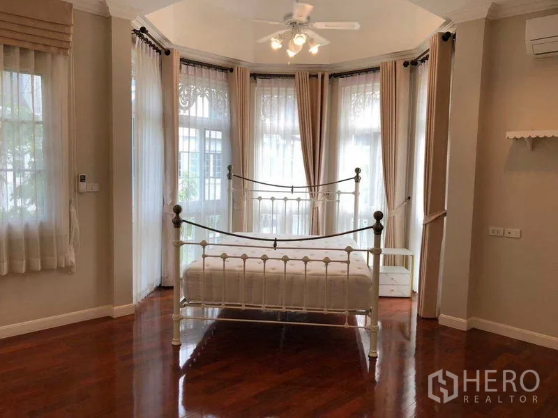 独立式住宅 出租在Bang Na, Bangkok - 采光充足的卧室，飘窗、纱帘与白色铁艺床。