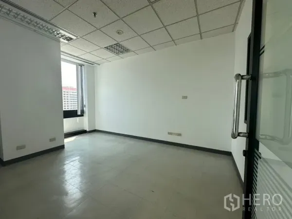 Office Space for rent in Khlong Toei, Bangkok - Bright private office with tiled floor and window overlooking city buildings.