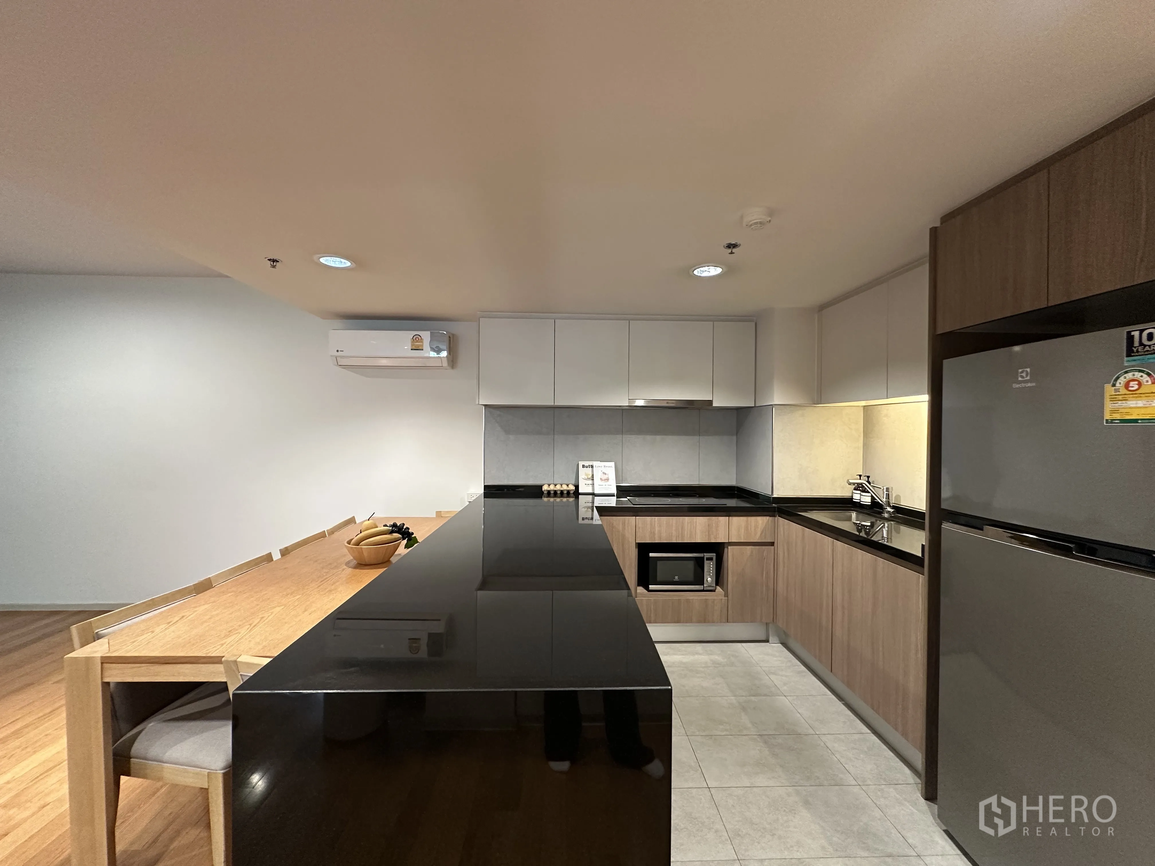 คอนโด for rent in Khlong Toei, Bangkok - ครัวสไตล์โมเดิร์นพร้อมไอส์แลนด์ท็อปหินสีดำ ตู้ไม้ และโต๊ะทานข้าว