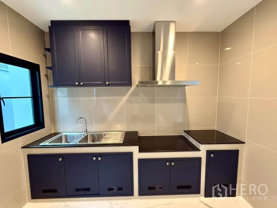Detached House for rent in Don Mueang, Bangkok - Close-up of kitchen with black countertops and stainless-steel range hood.