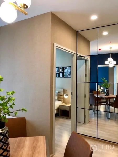 Condominium for rent or sale in Huai Khwang, Bangkok - Master bedroom with wooden bed, white bedding, navy feature wall, and large window with curtains.