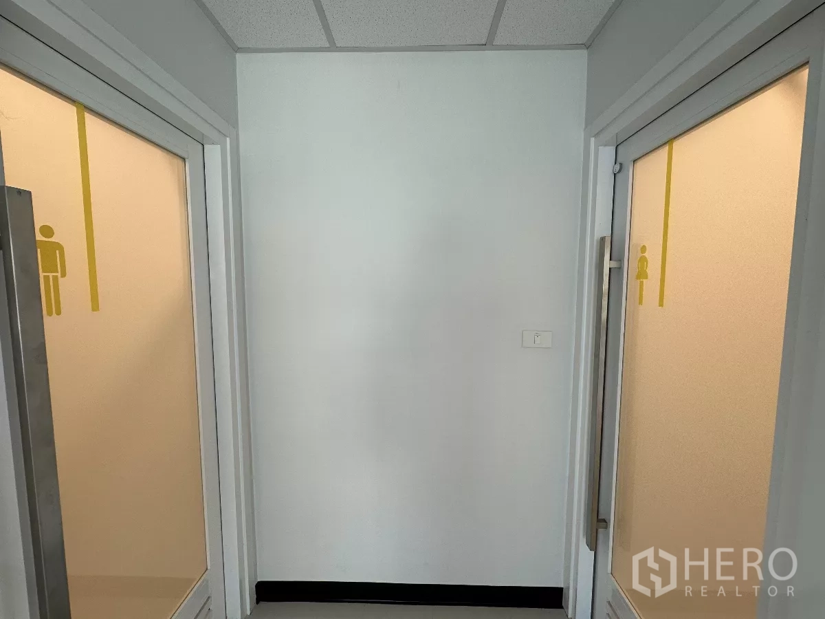 Office Space for rent in Watthana, Bangkok - Separate men’s and women’s restroom entrances with frosted glass doors in the office corridor.