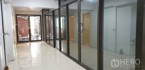 零售空间 出租在Chatuchak, Bangkok - 走廊两侧为落地玻璃隔间与滑门，适合办公室或展示区。