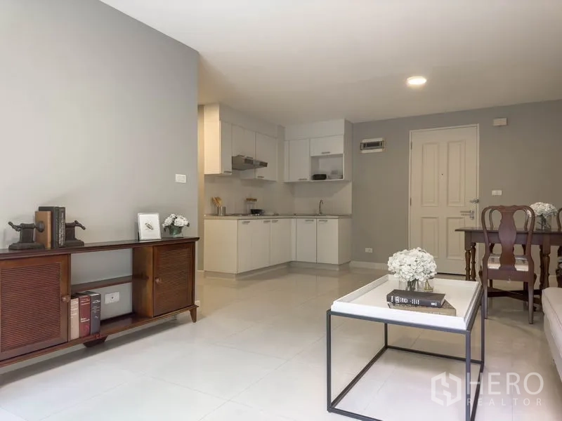 Condominium for sale in Watthana, Bangkok - Open-plan living, dining, and kitchen area with neutral decor.