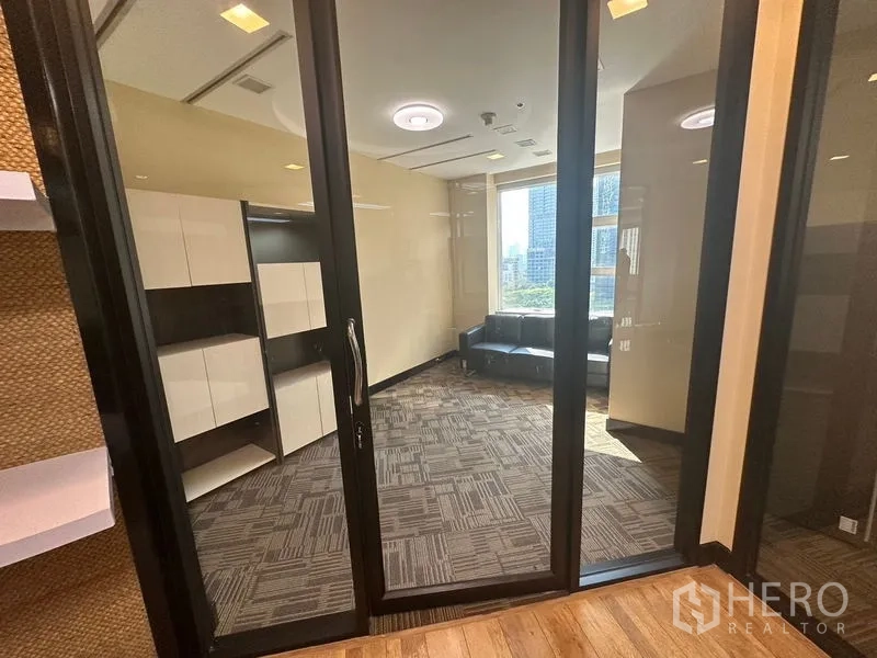 办公空间 出租 - 玻璃隔间的独立办公室，地毯地面，内置柜及靠窗沙发，可欣赏城市景观。