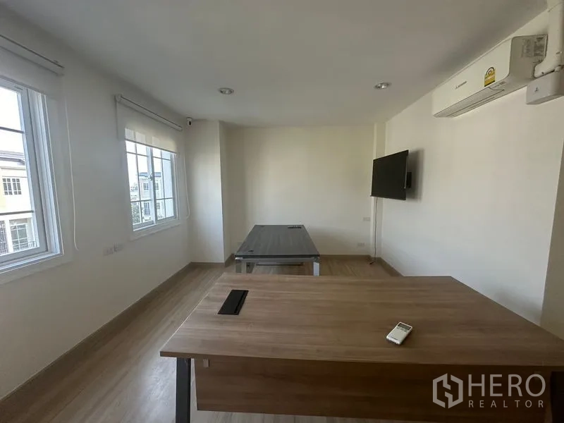 带办公室的家 出租在Bang Na, Bangkok - 带办公桌的办公室，墙装电视、空调与多扇窗户。