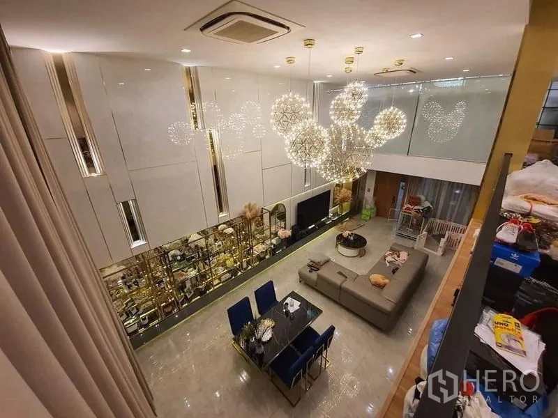 联排别墅 出售在Lat Phrao, Bangkok - 挑高客厅，设计感吊灯，转角沙发与餐桌一体。