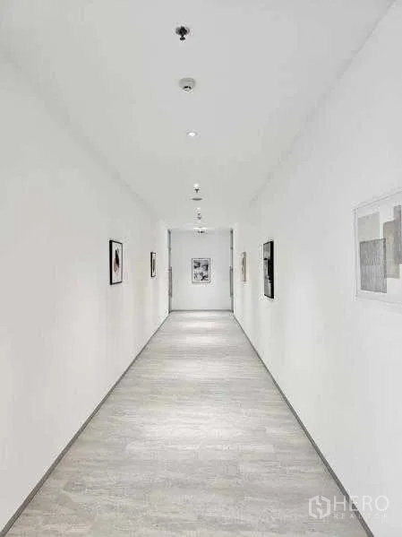 办公空间 出租在Bang Rak, Bangkok - 洁白走廊，嵌灯与装饰画，引向办公区域。
