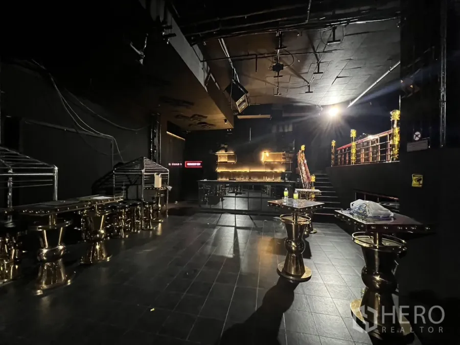 零售空间 出租 - 主层设有背光吧台、金色高脚桌和通往夹层的楼梯。