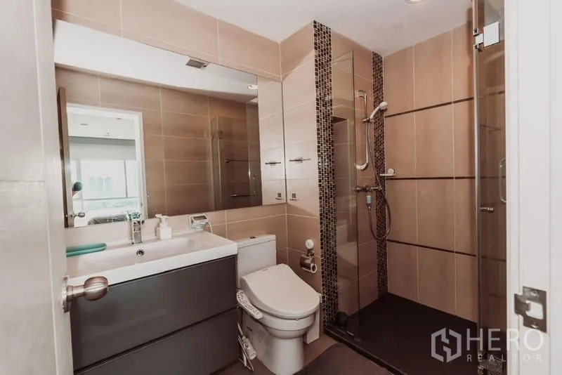 Condominium for rent in Sathon, Bangkok - Modern bathroom with walk-in glass shower, vanity, and toilet.