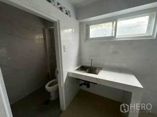 อาคารพาณิชย์ ให้เช่าในKhlong Toei, Bangkok - ซิงก์เคาน์เตอร์สีขาวใต้หน้าต่างบานเลื่อน ถัดจากประตูห้องน้ำ.