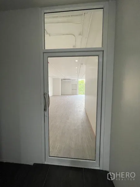 Office Space for rent in Bang Rak, Bangkok - Interior corridor view through a narrow glass door with transom window.