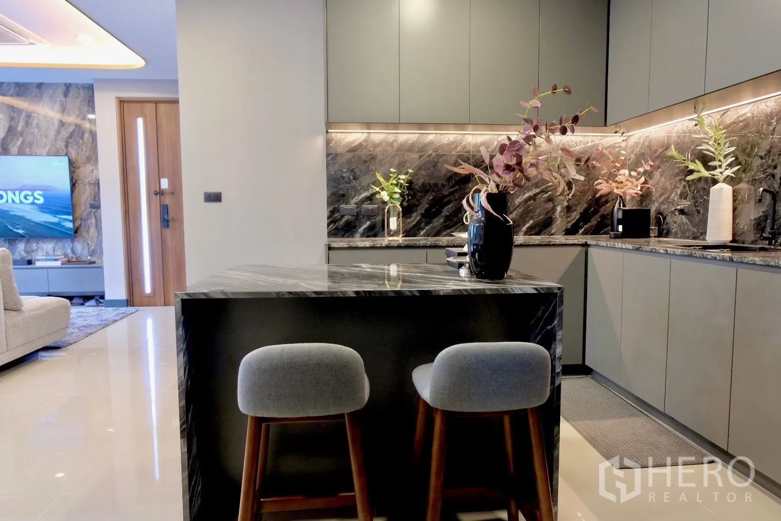 Semi-detached House for sale in Prawet, Bangkok - Contemporary kitchen with marble island and stools beside living area.