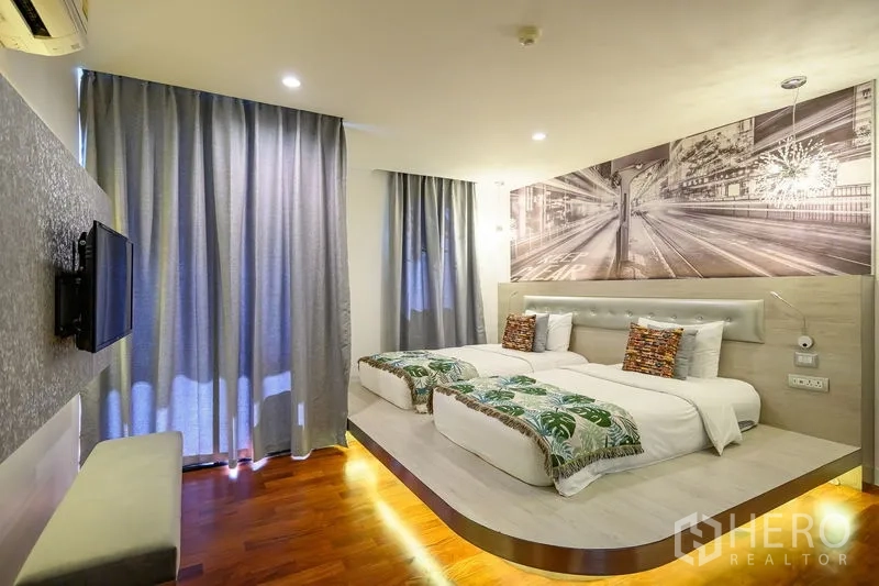 Condominium for rent in Pathum Wan, Bangkok - Twin bedroom on a raised platform with a graphic mural and blackout curtains.