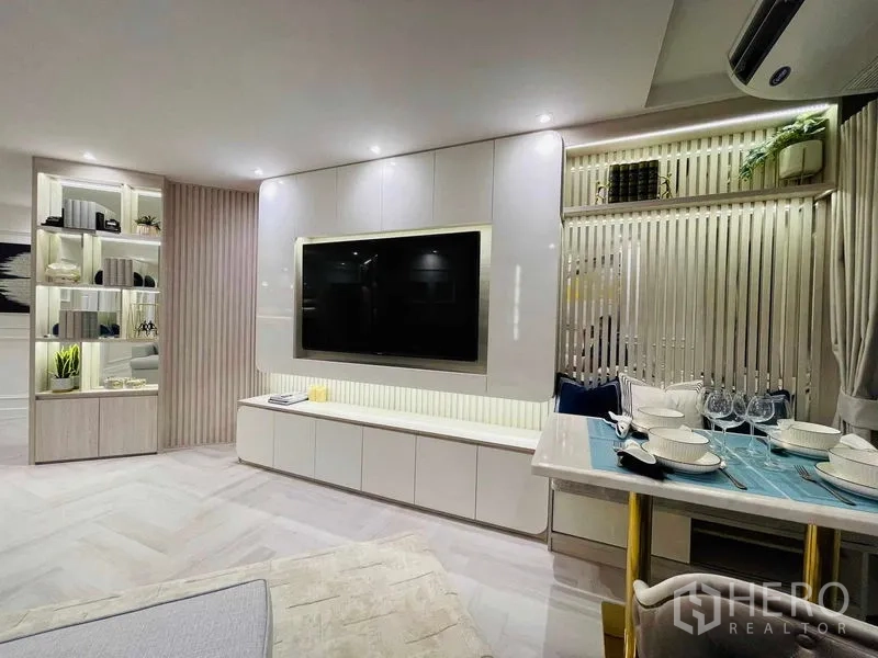 Condominium for sale in Yan Nawa, Bangkok - TV feature wall opposite dining nook with banquette seating and window curtains.