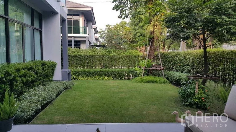 独立式住宅 出租在Prawet, Bangkok - 修剪整齐的侧院花园与绿色草坪。