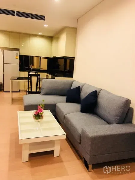 公寓 出租或出售在Bang Rak, Bangkok - 开放式客厅，灰色沙发与茶几相连，后方为紧凑厨房。