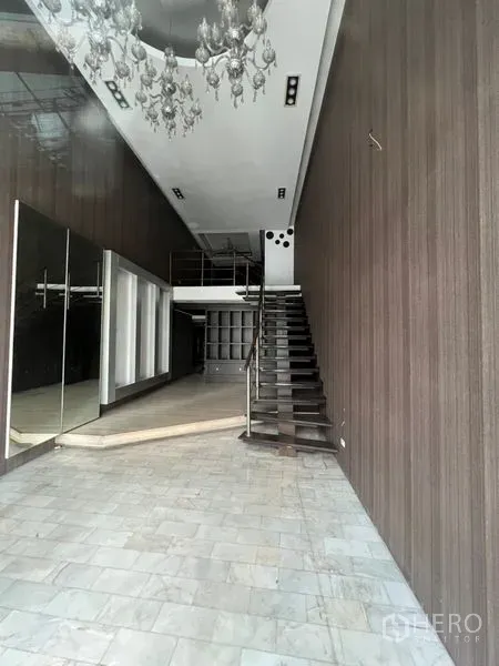 店屋 出租在Watthana, Bangkok - 挑高店面内饰，带夹层、楼梯与吊灯，木纹墙面和石材地面