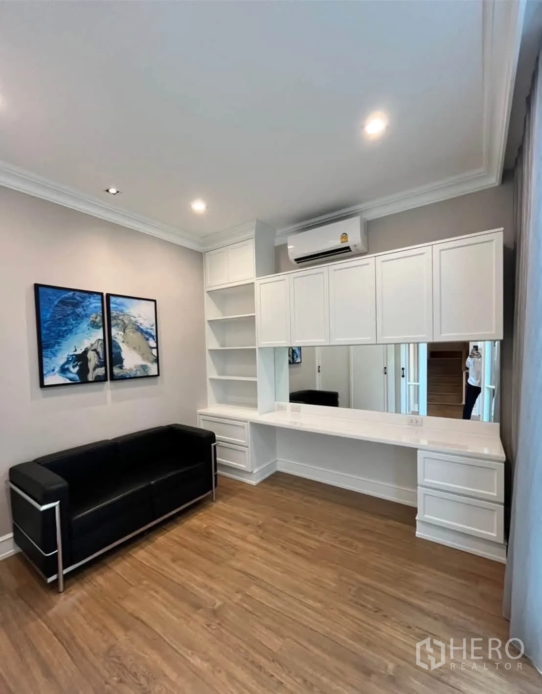 Townhouse for rent in Lat Phrao, Bangkok - Cozy room with black sofa and a long built-in vanity and cabinets.