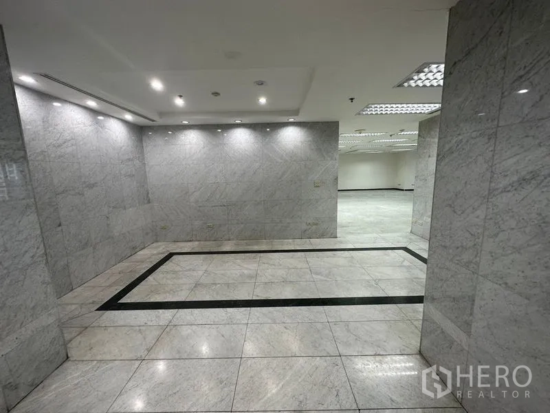 Office Space for rent in Khlong Toei, Bangkok - Marble-clad lobby and entrance corridor with recessed ceiling lights leading to the office.