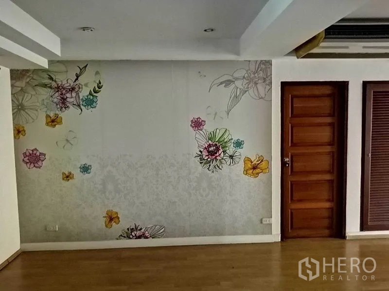 办公空间 出租在Khlong Toei, Bangkok - 带花卉主题墙的房间，旁有木门与木地板。