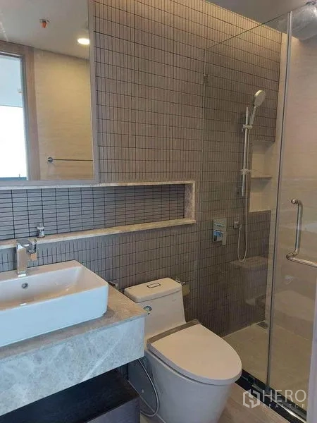 คอนโด ขายในPathum Wan, Bangkok - ห้องน้ำสว่าง มีฝักบัวกั้นกระจก เคาน์เตอร์อ่างล้างหน้า และโถสุขภัณฑ์
