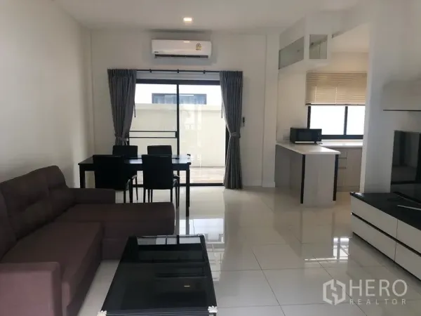 Townhouse for rent in Saphan Sung, Bangkok - Open-plan living and dining area with sofa set, dining table and sliding glass doors to a terrace.