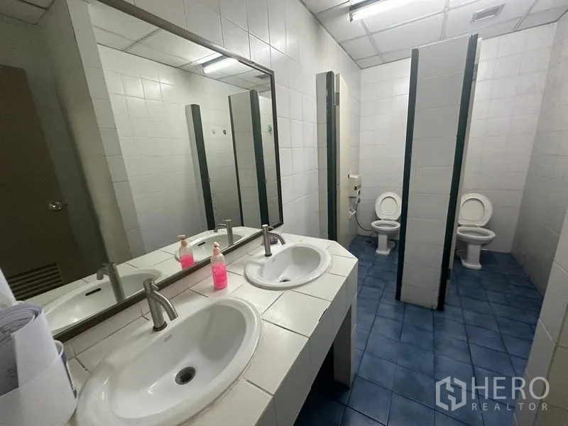 Office Space for rent - Restroom with stalls and twin sinks on a blue-tiled floor
