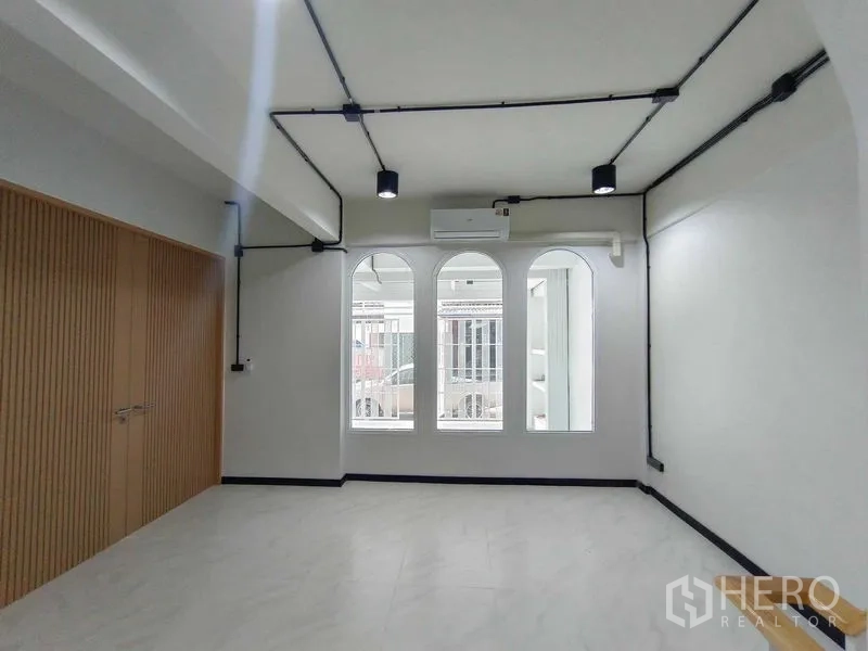 Townhouse for sale in Bang Phlat, Bangkok - Bedroom or office with arched windows, wood built-in wardrobe and ceiling spotlights.