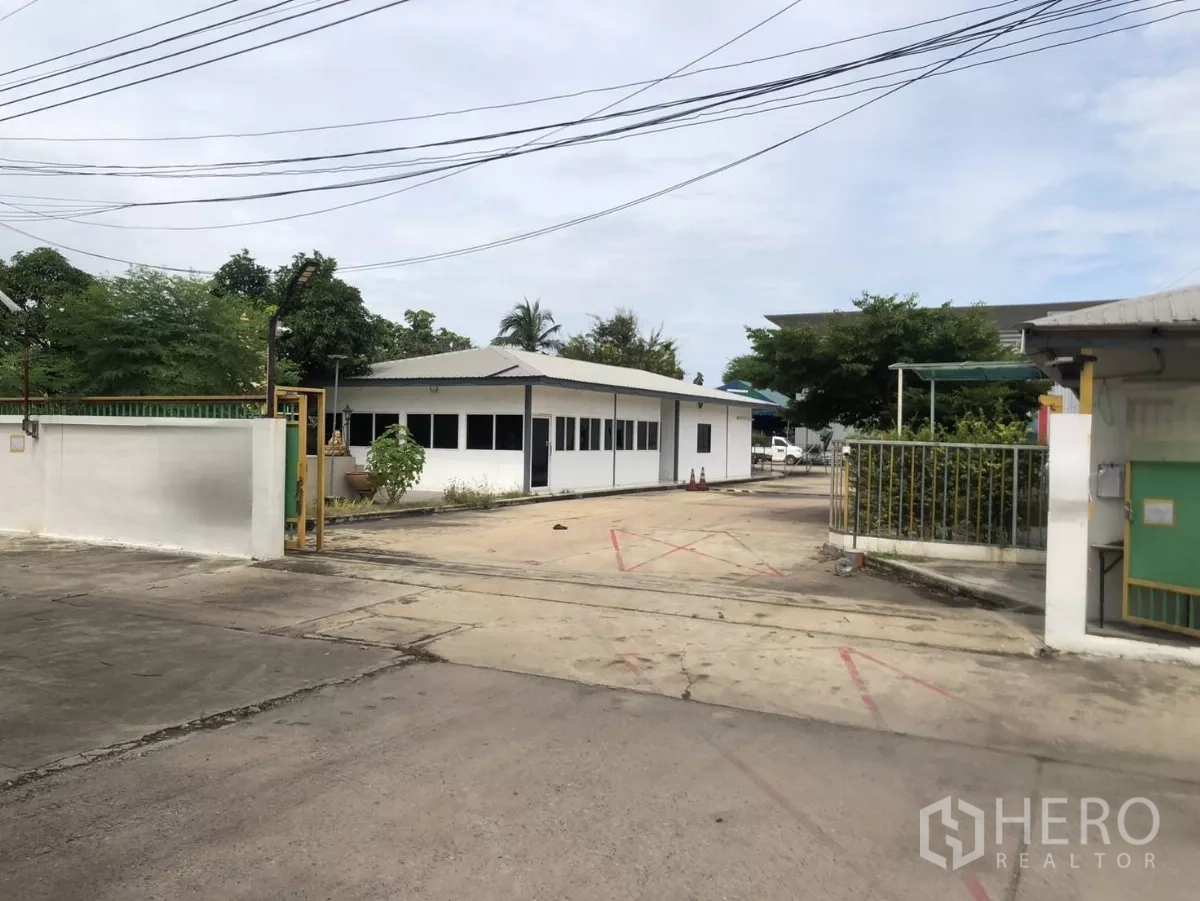 Factory for rent in Mueang Samut Prakan, Samut Prakan - Wide entrance with guard gate and single-storey office beside driveway