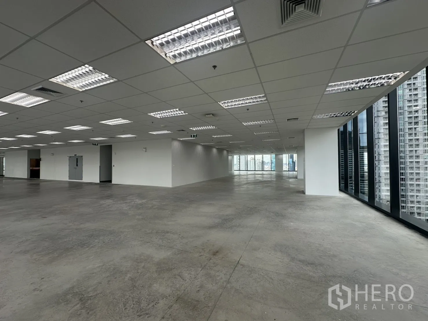 Office Space for rent in Ratchathewi, Bangkok - Open office floor with exposed concrete, grid lighting, and emergency exit doors.