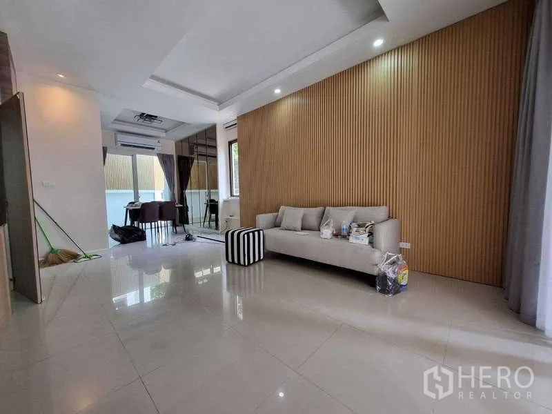 ทาวน์เฮาส์ ให้เช่าในWang Thonglang, Bangkok - โถงนั่งเล่นและทานอาหาร โซฟา ผนังเซาะร่องลายไม้ และพื้นกระเบื้องเงา