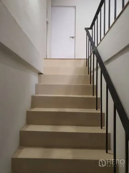 อาคารพาณิชย์ ให้เช่าในPhra Khanong, Bangkok - บันไดภายในขั้นสีครีมพร้อมราวเหล็กสีดำและประตูสีขาวด้านบน