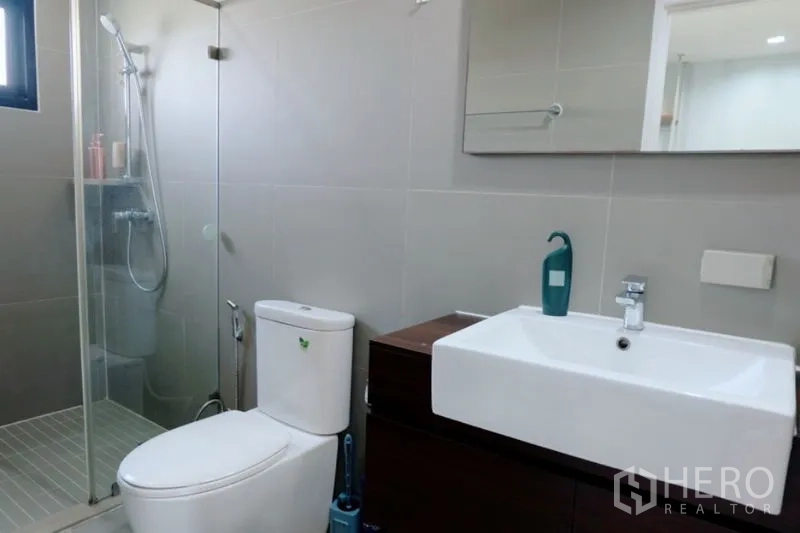 Townhouse for rent in Khlong Toei, Bangkok - Second bathroom featuring walk-in shower, toilet and mirror above a wood vanity.