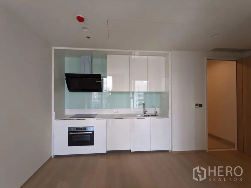 Condominium for sale - Open-plan white kitchen with built-in oven, cooktop, extractor, and glass backsplash.