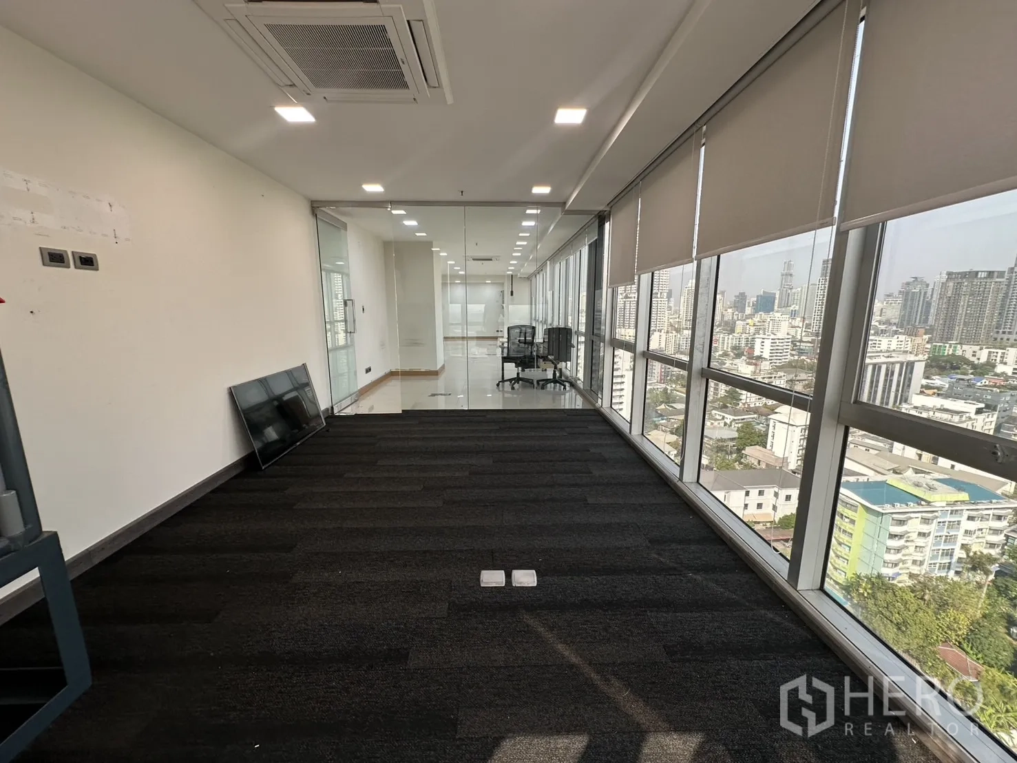 Office Space for rent - Carpeted room facing a glass partition and window wall with city views.
