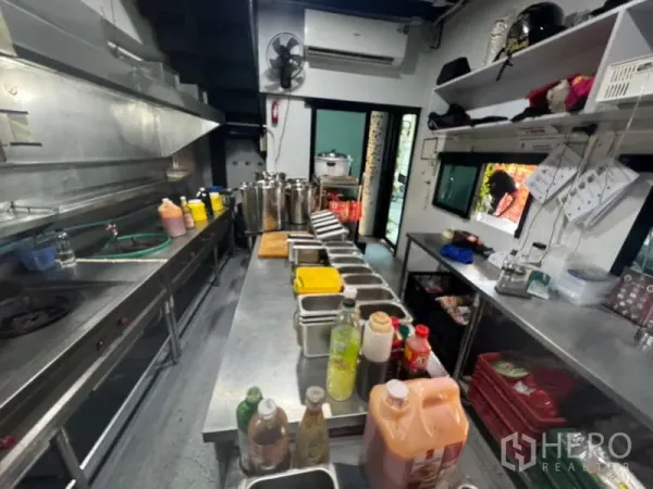 零售空间 出租在Ratchathewi, Bangkok - 长不锈钢备餐台、置物架与设备齐全的商用厨房。