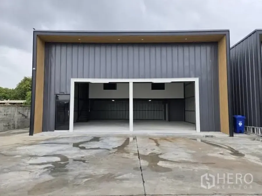 Warehouse for rent - Front elevation of modern dark-panel warehouse with twin wide openings and a concrete forecourt.