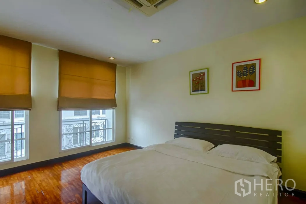 Townhouse for rent in Watthana, Bangkok - Cozy guest bedroom with two windows, blinds and wood flooring.