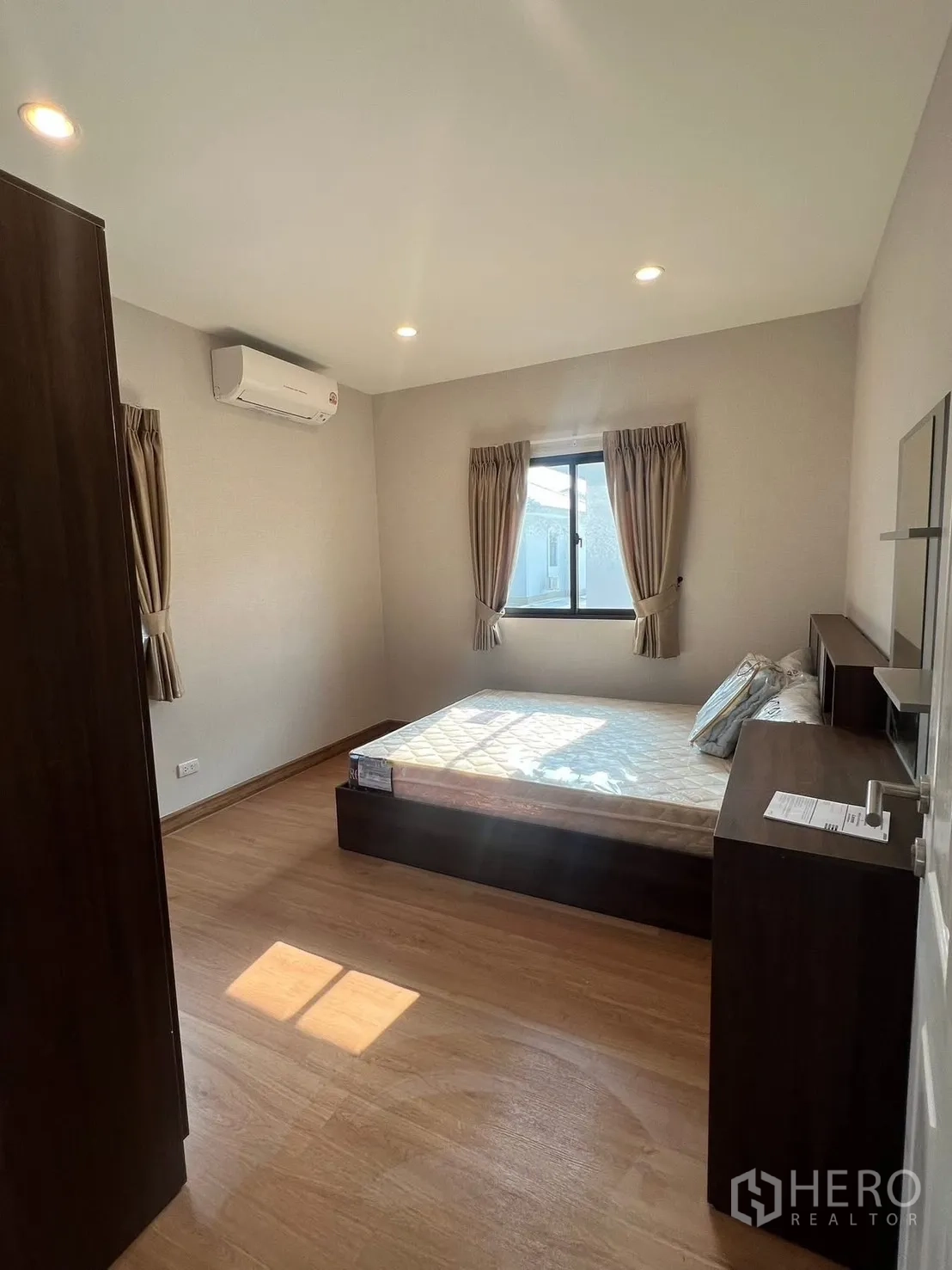 Detached House for rent in Bang Phli, Samut Prakan - Bright bedroom with wooden floor, bed frame, curtains and air conditioning.
