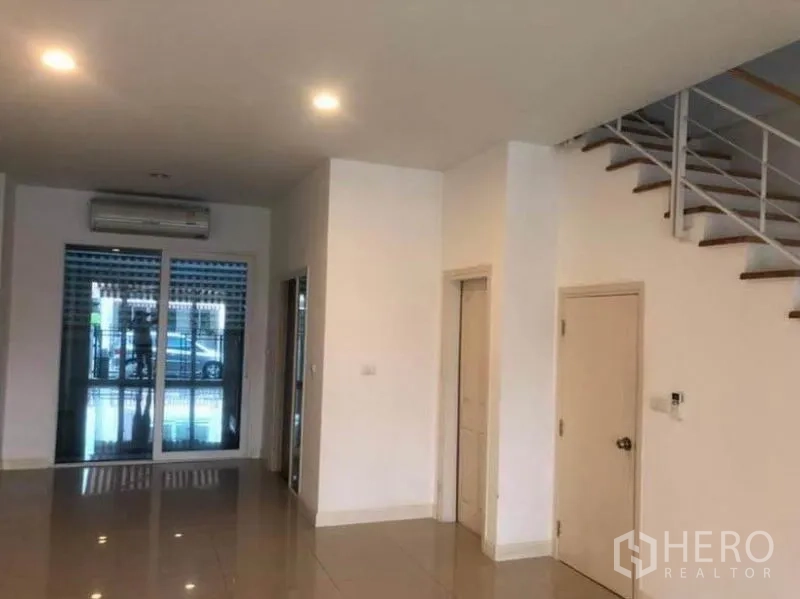 ทาวน์เฮาส์ ให้เช่าในWang Thonglang, Bangkok - พื้นที่นั่งเล่นชั้นล่างสว่าง พื้นกระเบื้องเงา ไฟดาวน์ไลท์ ประตูกระจกบานเลื่อน และบันได