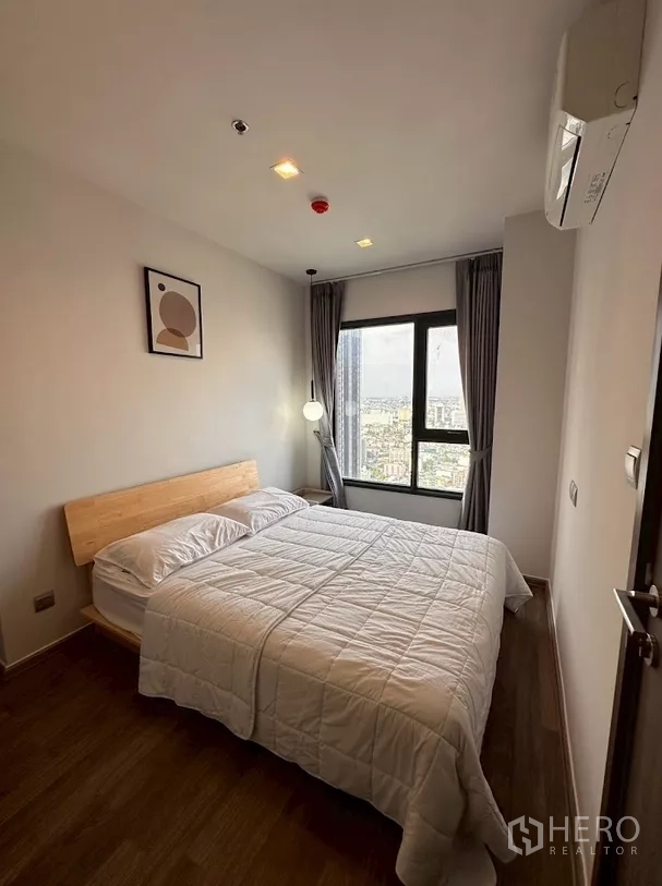 Condominium for rent in Chatuchak, Bangkok - Second bedroom with bed, pendant light and wide city views.