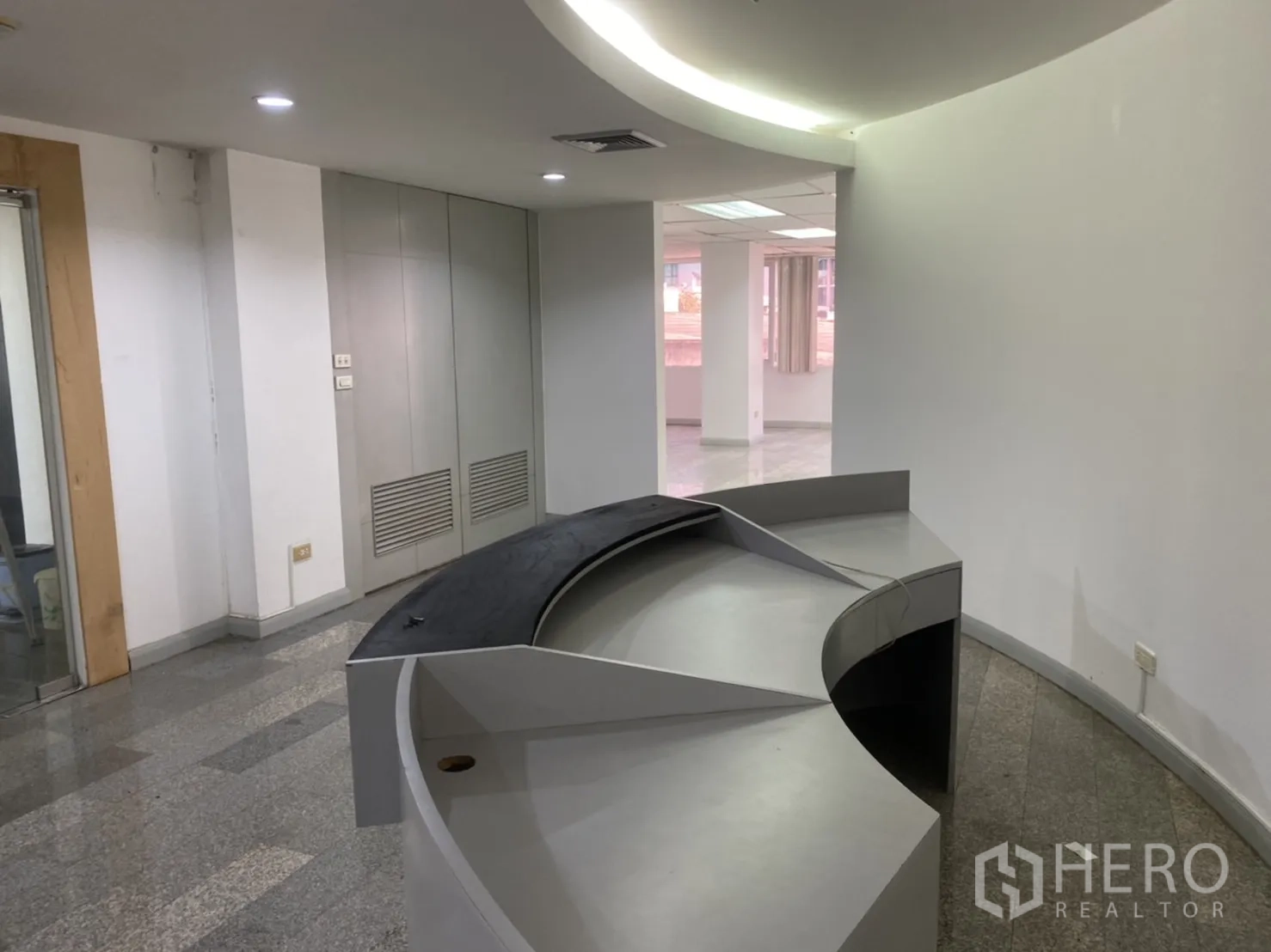 Office Space for rent in Khlong Toei, Bangkok - Curved reception counter with spotlight ceiling and polished stone floors.