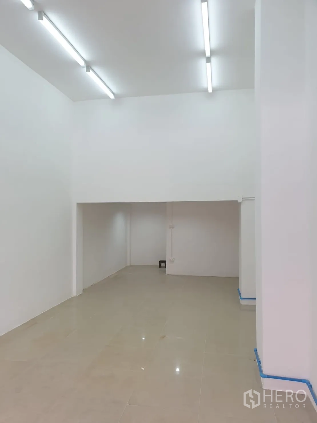 零售空间 出租在Chatuchak, Bangkok - 白色店铺内景，挑高天花、亮面瓷砖地面与后方储物区。