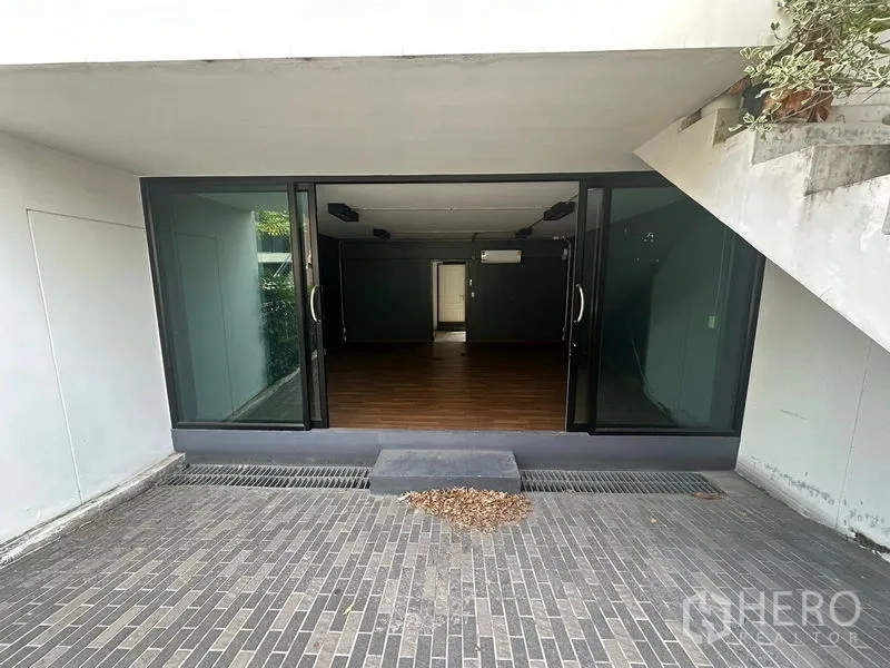 Home Office for rent in Phra Khanong, Bangkok - Ground-level entrance with sliding glass doors opening to a wood-floored room.