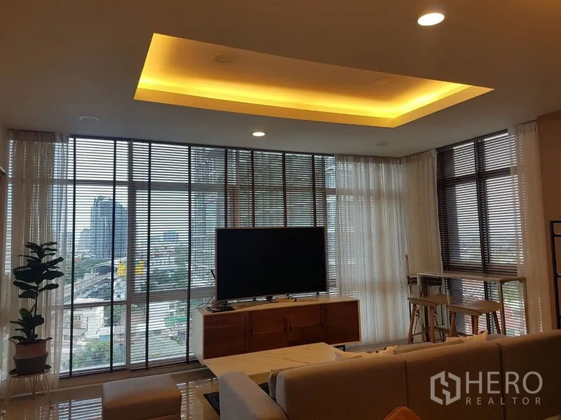 公寓 出租或出售在Bang Na, Bangkok - 客厅设落地窗与天幕灯，可欣赏城市景观，配电视柜。