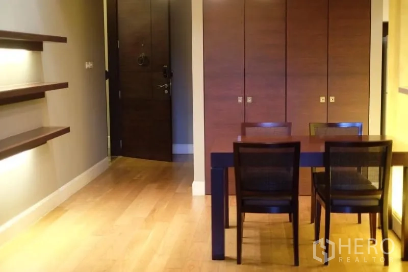 Condominium for rent in Watthana, Bangkok - Dining table for four beside built-in wall shelves and floor-to-ceiling storage cabinets.