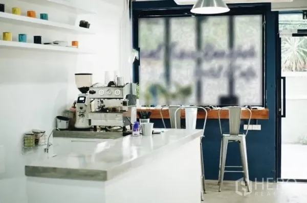 อาคารพาณิชย์ ให้เช่าในKhlong Toei, Bangkok - เคาน์เตอร์สไตล์คาเฟ่สว่างพร้อมเครื่องชงกาแฟ ชั้นวาง และสตูลริมหน้าต่างบานใหญ่