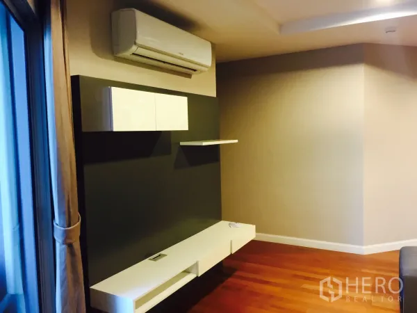 Condominium for rent in Huai Khwang, Bangkok - Minimalist media wall with floating shelves and split air conditioner beside a large window.